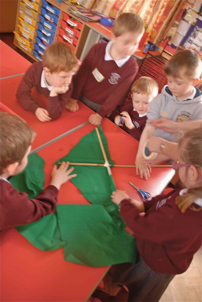 Ann helped another group of children to plan the kite. The children are using two bamboo sticks taped together as the structure of the kite and crepe paper for the kite body.