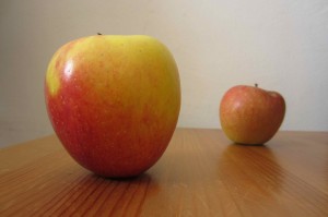 Two apples on table at different distances